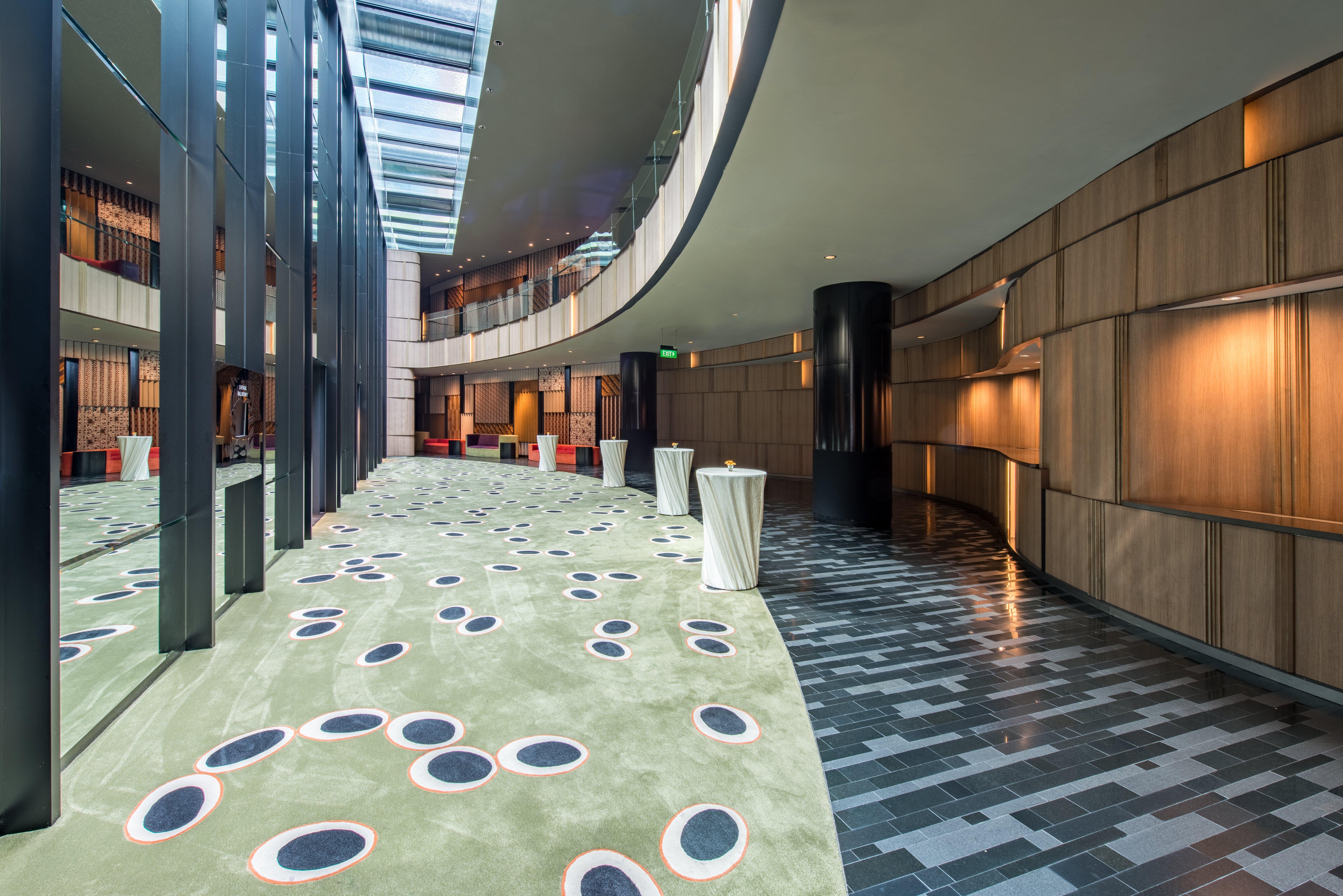 Crowne Plaza Changi Airport By Ihg Singapore Exterior photo The photo shows a modern indoor space that features a curved hallway with a mix of materials and textures. The floor is divided into two sections: one has a smooth, dark tiled design, while the other has a soft, green carpet with circular patterns in