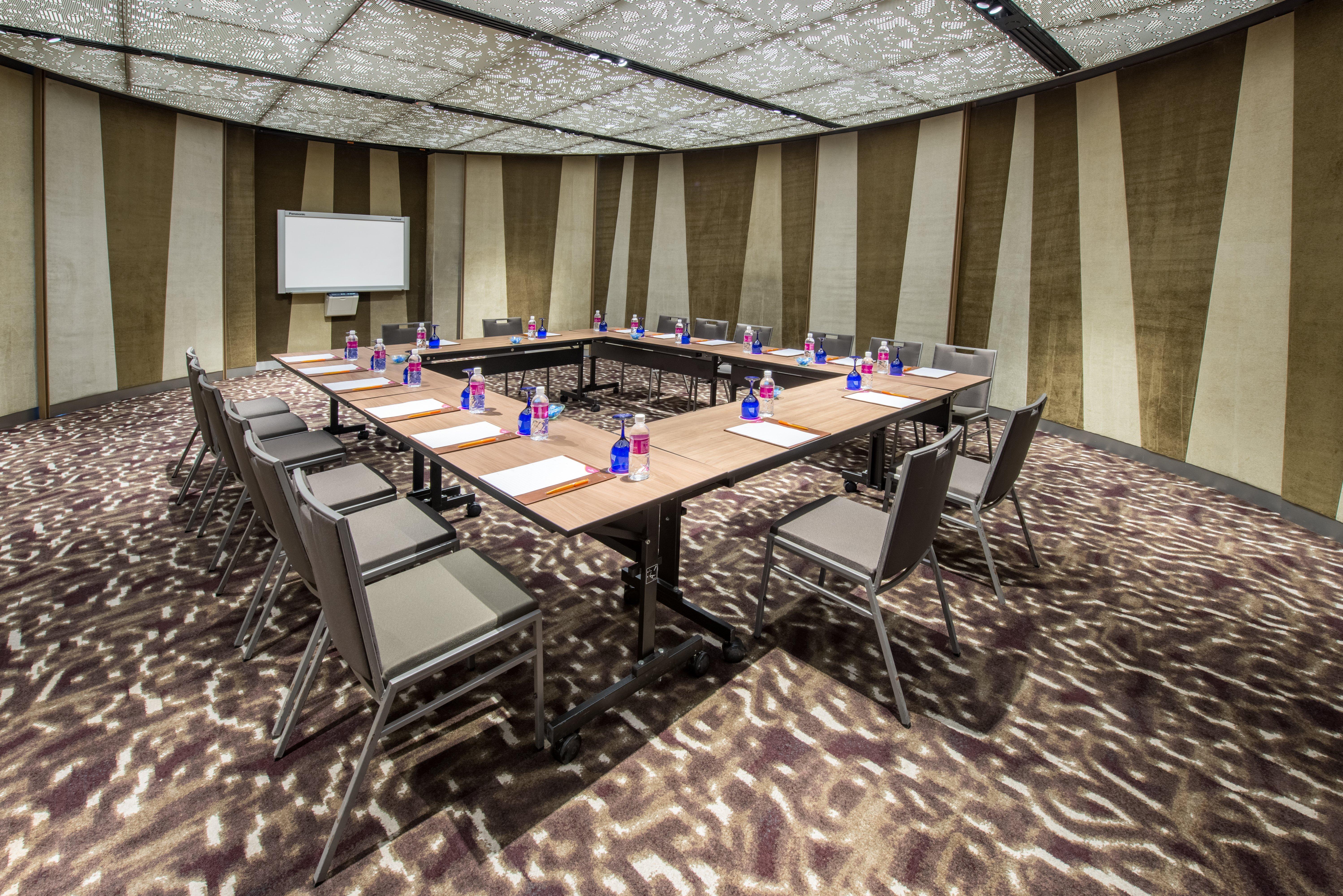 Crowne Plaza Changi Airport By Ihg Singapore Exterior photo The photo depicts a conference room set up for a meeting. There is a large rectangular table in the center with chairs arranged around it. Each seating area has a small bottle of water and a notepad, suggesting it's prepared for attendees. The room f