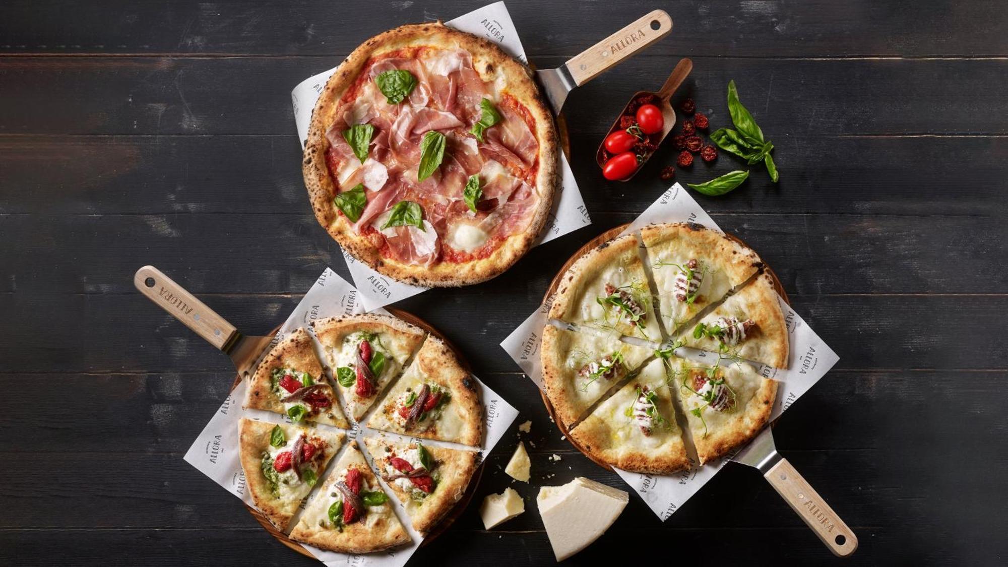 Crowne Plaza Changi Airport By Ihg Singapore Exterior photo The photo depicts three different types of pizzas on wooden serving paddles. 

1. **Top Pizza**: This pizza features a combination of thinly sliced cured meats, likely prosciutto, alongside fresh basil leaves and mozzarella cheese on a light-colored 