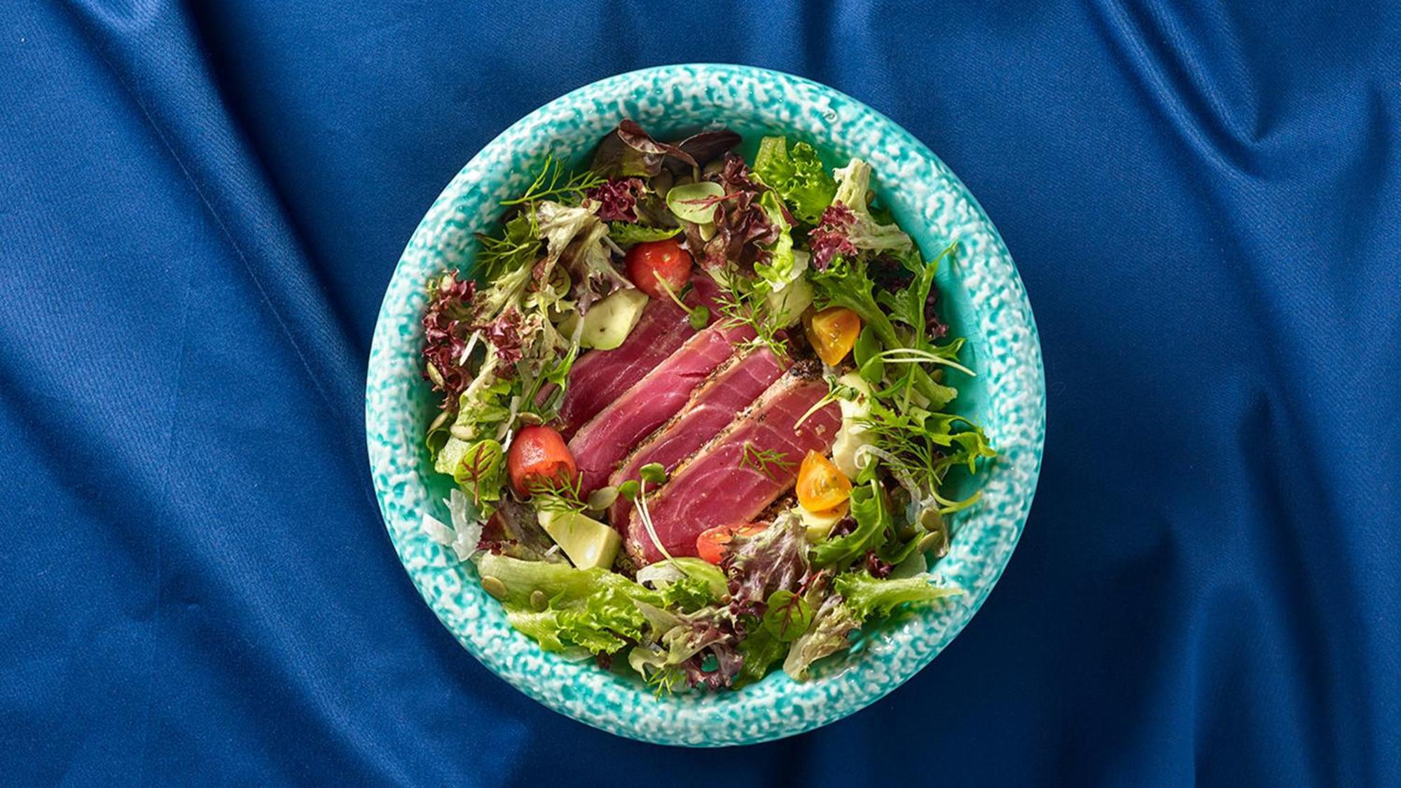 Crowne Plaza Changi Airport By Ihg Singapore Exterior photo The photo shows a bowl of salad featuring a variety of fresh leafy greens, including different types of lettuce. There are sliced pieces of seared tuna placed over the salad, adding a protein element. The salad is garnished with cherry tomatoes and p