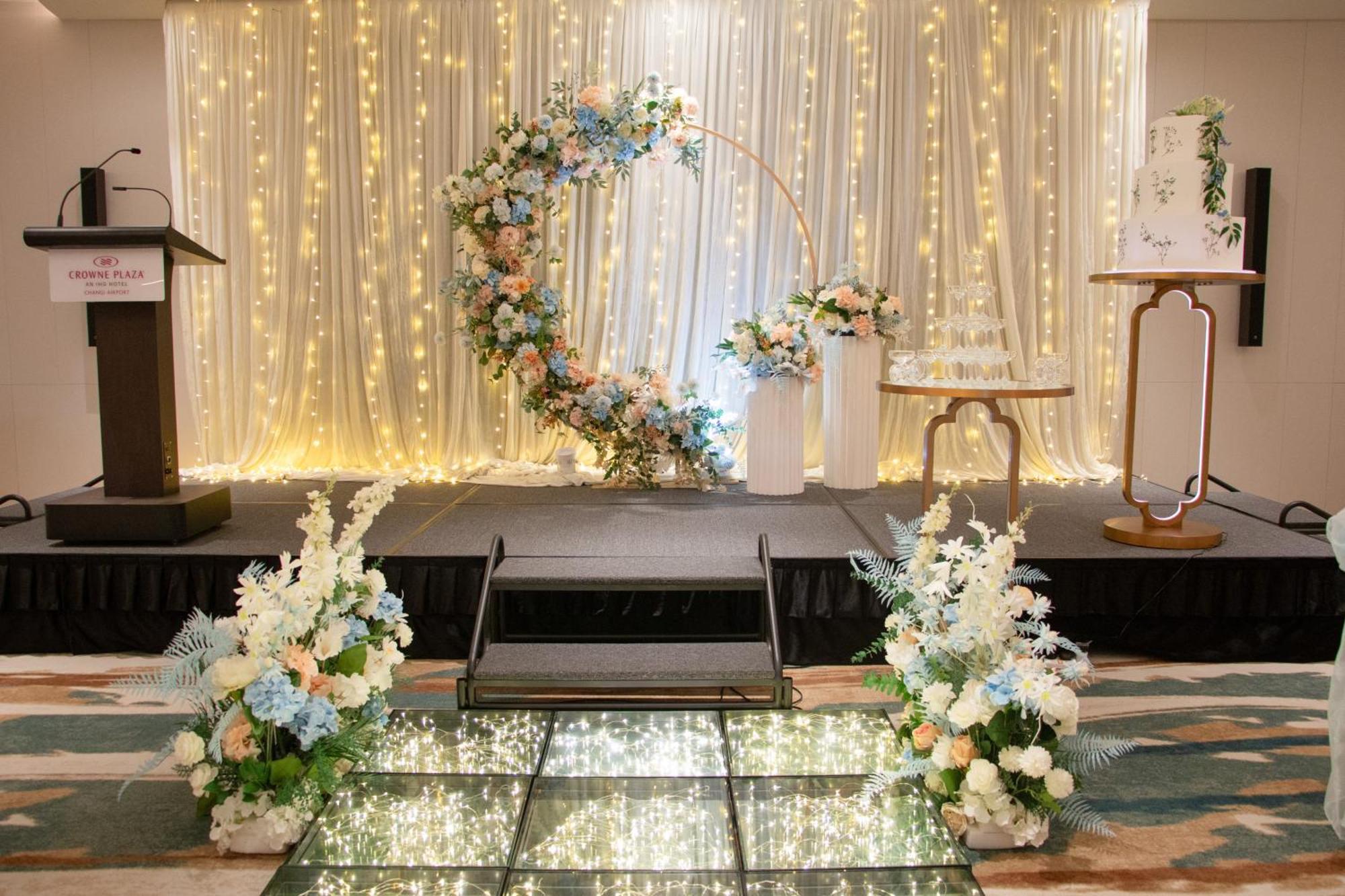 Crowne Plaza Changi Airport By Ihg Singapore Exterior photo The photo shows a beautifully decorated event space, likely for a wedding or special occasion. In the background, there is a shimmering curtain with fairy lights that create a warm, romantic ambiance. 

At the center, there is a circular floral arch 