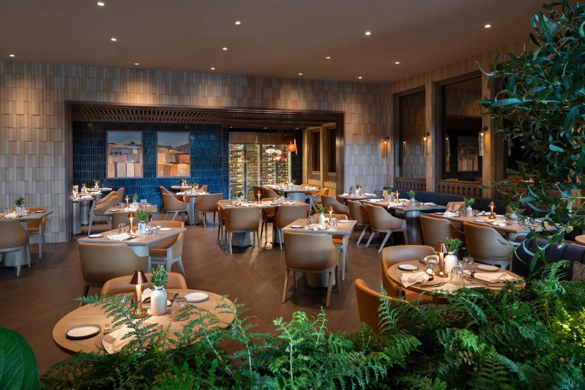 Crowne Plaza Changi Airport By Ihg Singapore Exterior photo The photo shows an upscale restaurant interior. It features multiple tables set with plates and decorative items, arranged in a spacious area. The design includes modern furnishings, with light wood and neutral tones dominating the decor. There are l