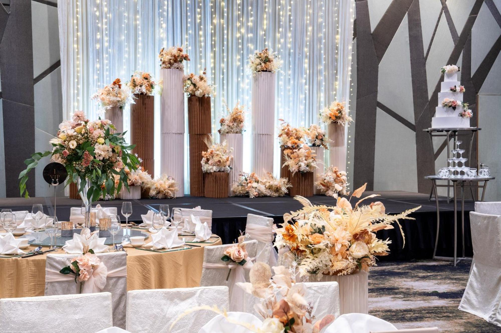 Crowne Plaza Changi Airport By Ihg Singapore Exterior photo The photo shows an elegantly decorated wedding reception. In the background, there are tall columns adorned with floral arrangements in soft, pastel colors. These floral displays are complemented by string lights hanging above, creating a romantic am