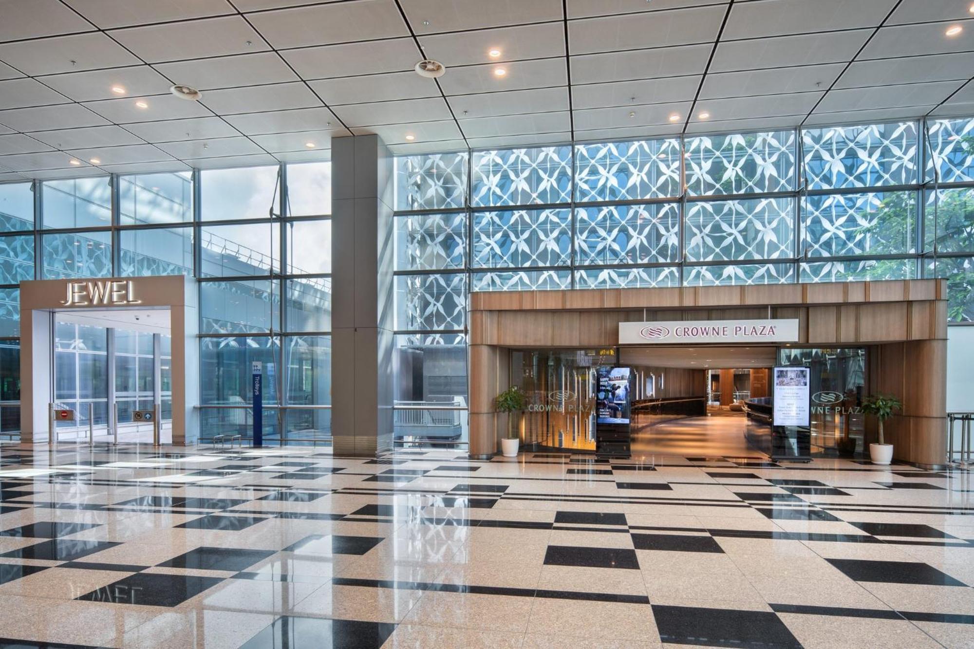 Crowne Plaza Changi Airport By Ihg Singapore Exterior photo The photo shows an indoor area with a modern architectural design featuring large glass windows that allow natural light to enter. On the left side, there is a sign for "JEWEL," indicating a retail or entertainment space. In the center, there is a wo