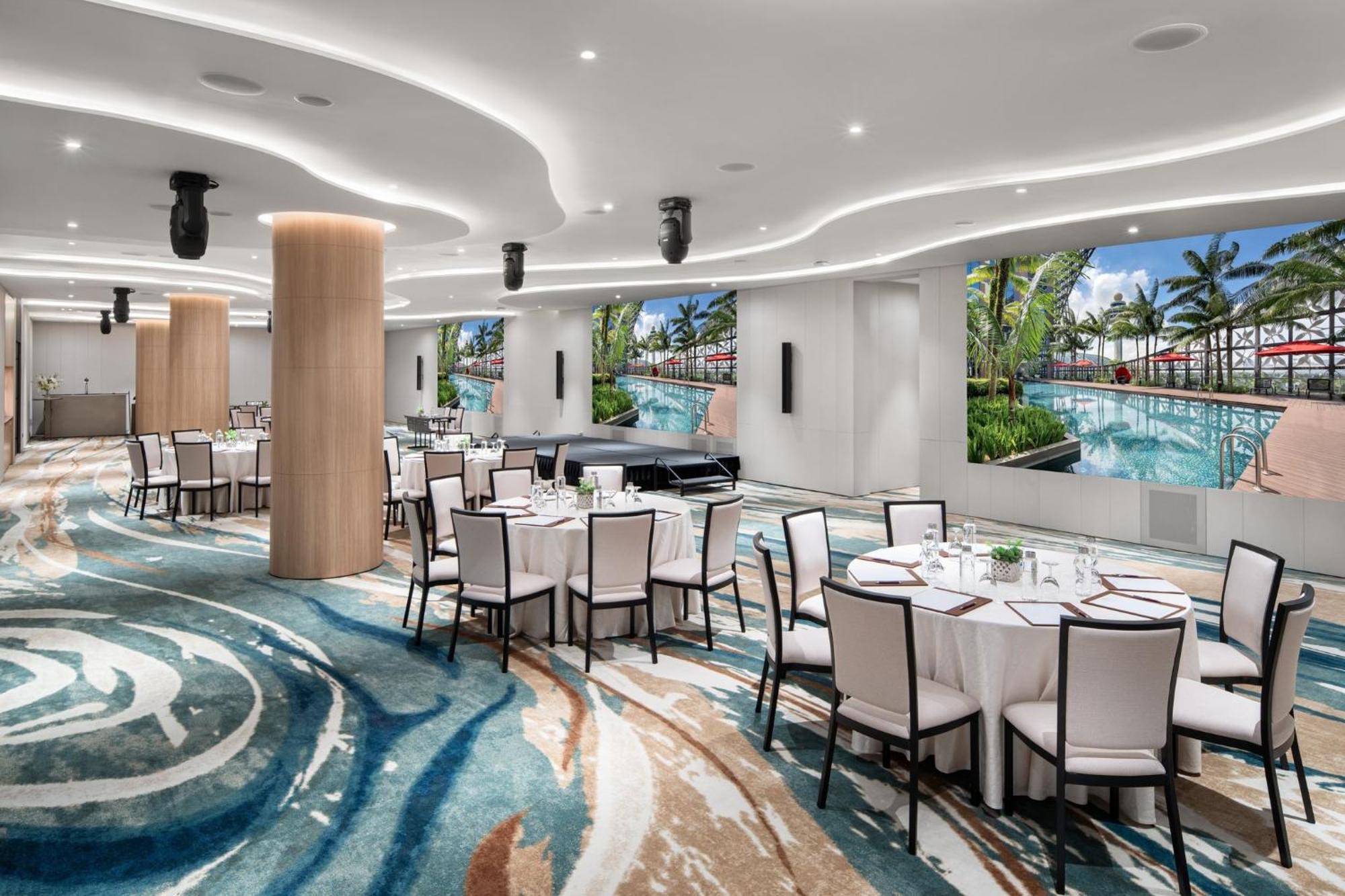 Crowne Plaza Changi Airport By Ihg Singapore Exterior photo The photo showcases a modern event space or dining area. It features several round tables covered with white tablecloths and set with dishes and utensils. The floor has an eye-catching design with swirling patterns in various shades of blue and beige